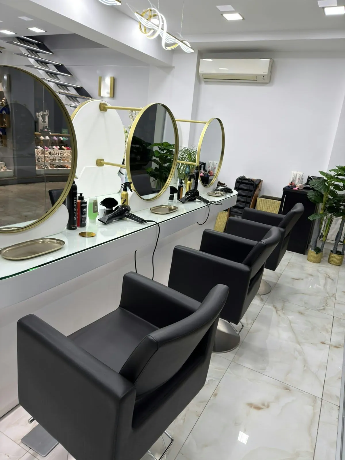 Θέσεις styling με στρογγυλούς χρυσούς καθρέφτες και μαύρες δερμάτινες πολυθρόνες